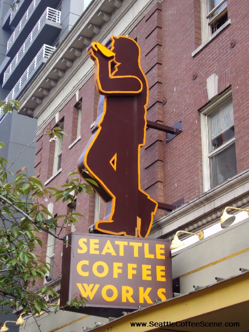 The large Seattle Coffee Works sign enjoys a cup of coffee as it towers over throngs of tourists headed to Pike's Place Market.